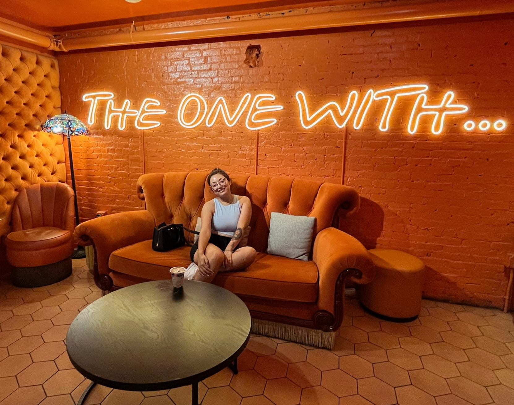 Mariah sitting on an orange couch at a Friends-themed café